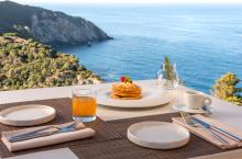 Pancakes and juice with a coastal view.